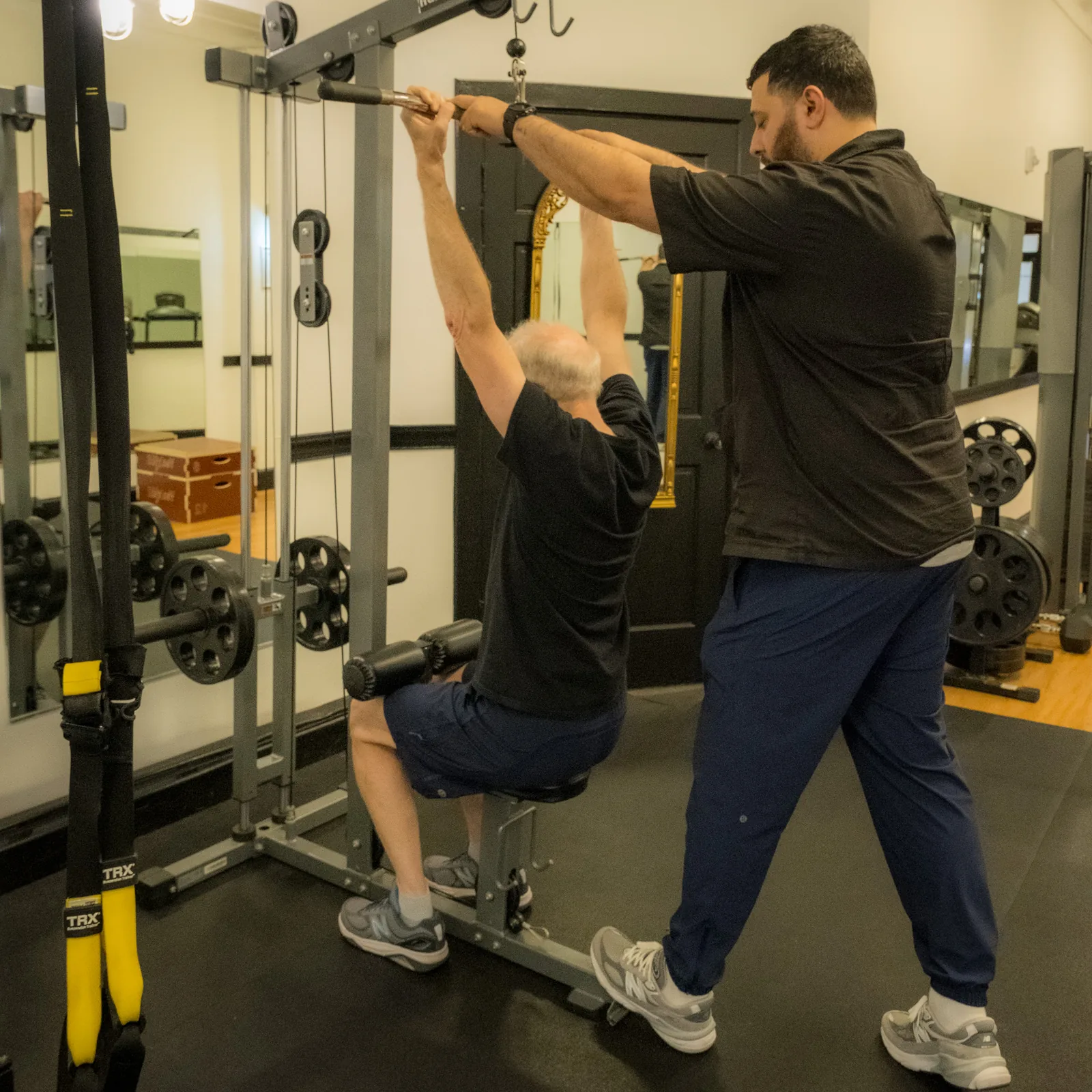 Trainer assisting a client with a controlled strength exercise